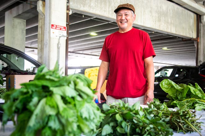 Nam Lam poses during the Iowa City Farmers Market on July 2. The Vietnamese immigrant, along with his wife Anna, have seen their produce increase in popularity during 13 years as vendors.